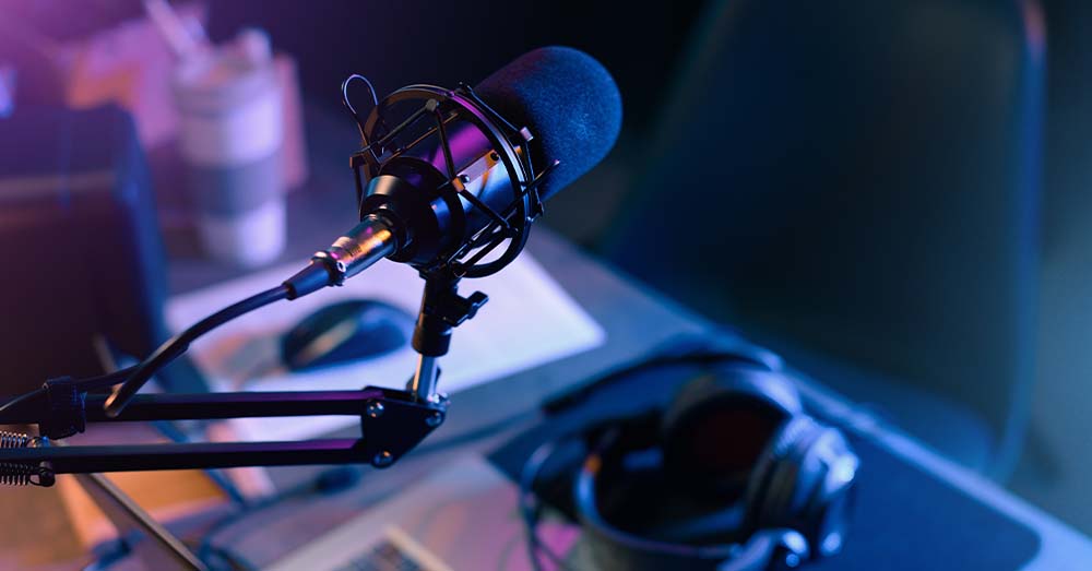 Un micrófono profesional y unos cascos que están encima de un ordenador