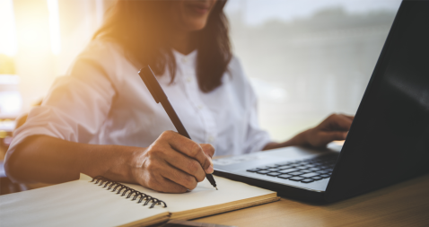 Una mujer escribiendo sobre un cuaderno