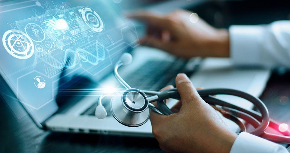 Profesional sanitario con un estetoscopio frente a un portátil con gráficos e iconos digitales de datos médicos superpuestos.